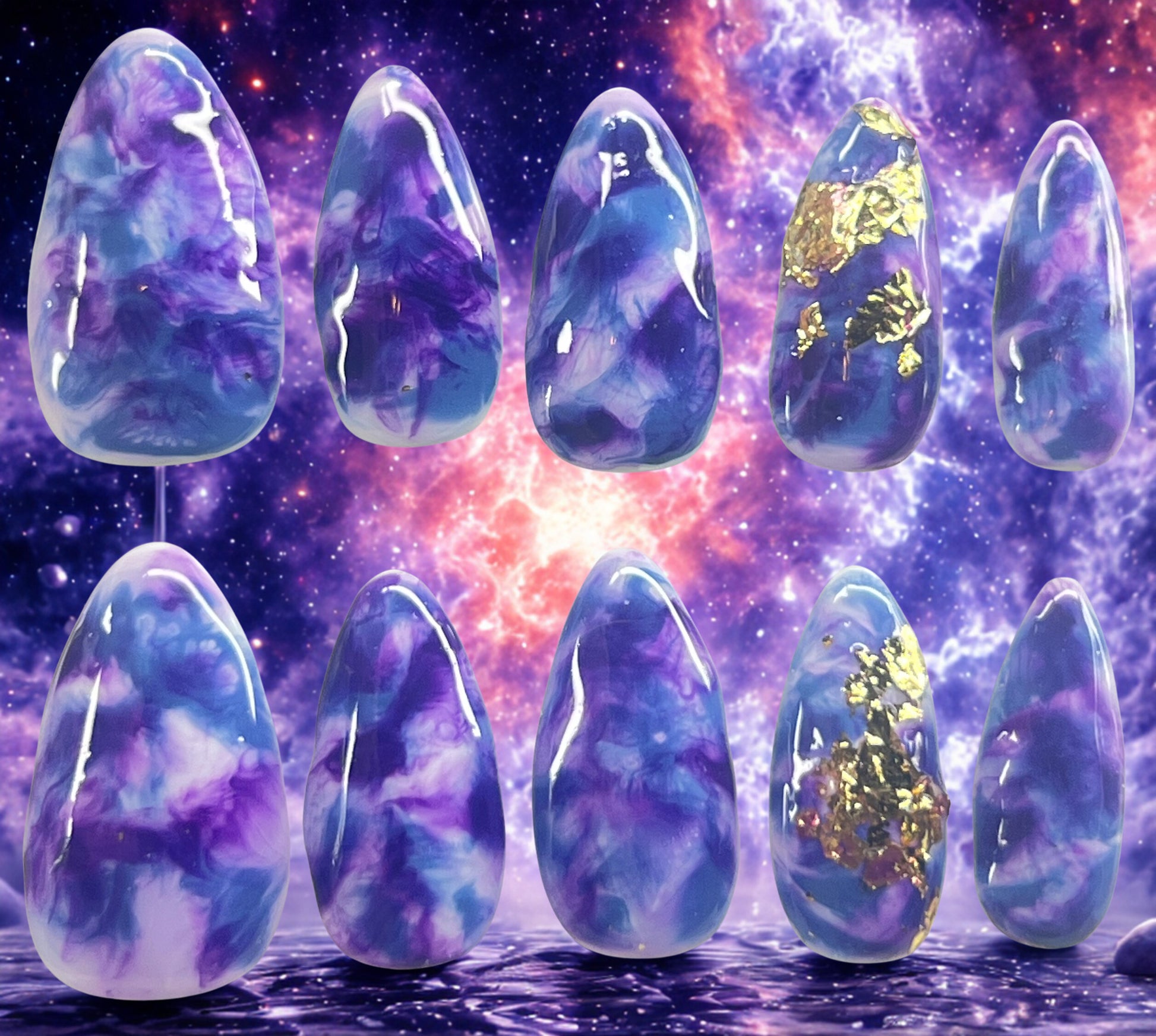 Cosmic Mist press-on nails featuring a white base with hand-painted dark blue and purple marble nebula effects. Ring fingers are decorated with textured gold foil. Medium almond shape shown against a vibrant purple and orange galaxy backdrop.