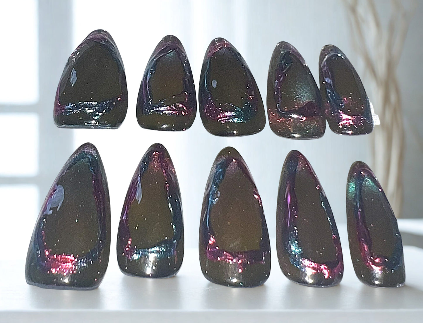 Cosmic Mirror press-on nails featuring a multi-chrome cat-eye center that shifts between purple and teal. The nails are surrounded by a hand-painted isolated chrome frame in pink and teal. Medium almond shape with a high-gloss, 3D metallic effect.