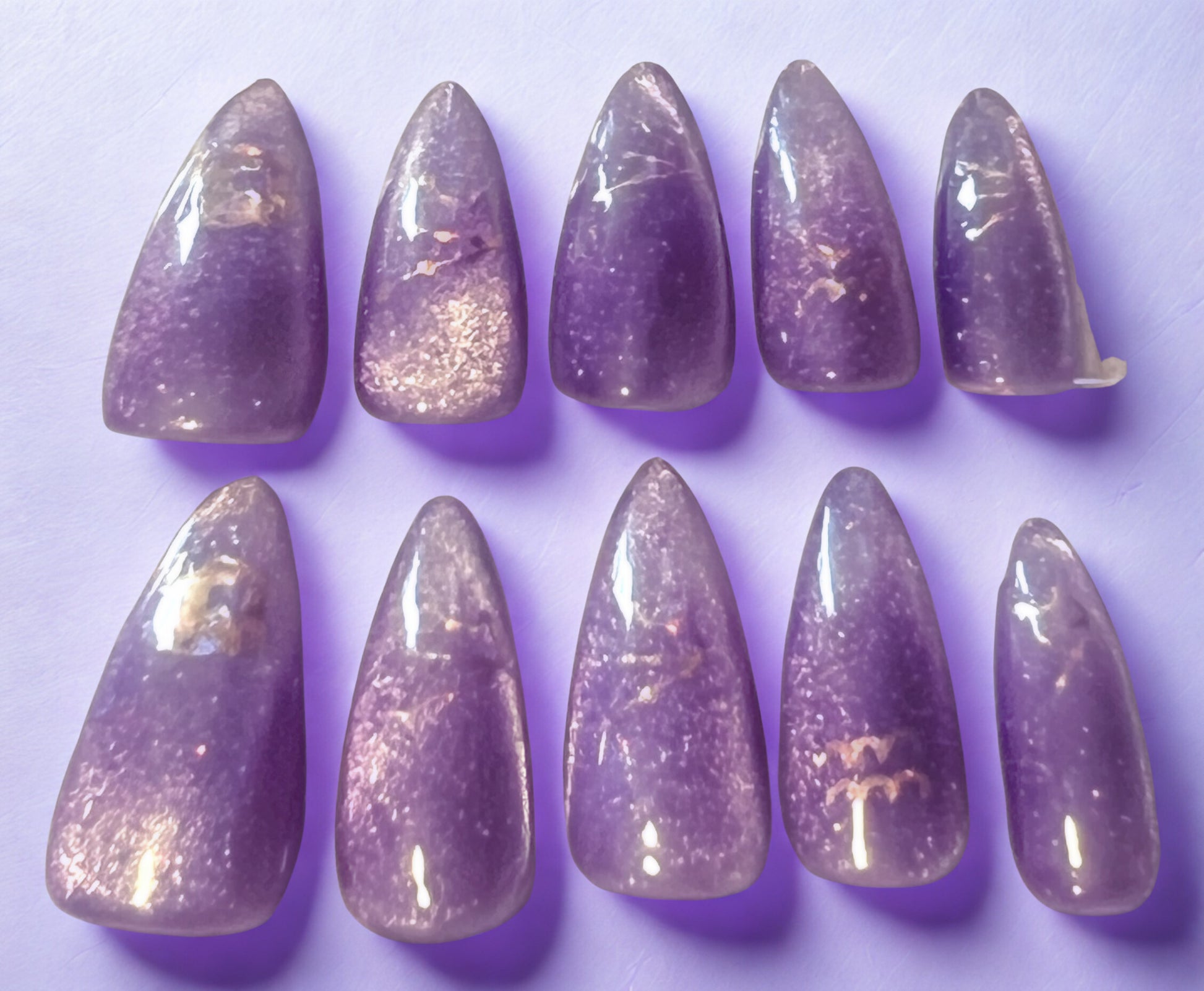 Shimmering Aquarius press-on nails featuring a lavender base with a gold magnetic velvet cat-eye shimmer. Decorated with holographic Aquarius zodiac water-bearer symbols. Medium stiletto-almond shape with a high-gloss finish.
