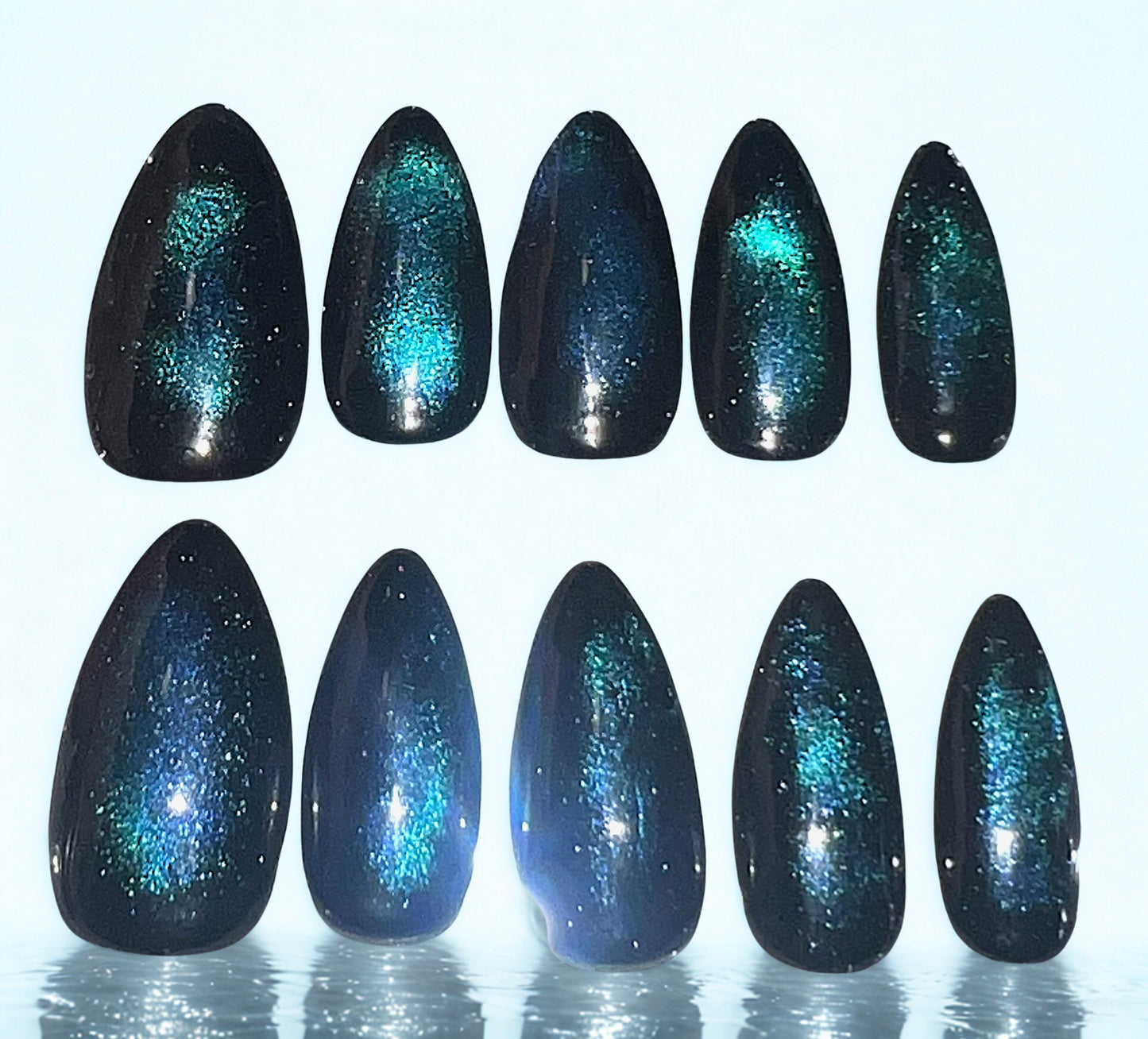 Cosmic Bloom press-on nails featuring a teal magnetic cat-eye shimmer bloomed into a solid black base. The teal pigment creates a soft, glowing aura effect in the center of each nail. Medium almond shape with a high-gloss finish.