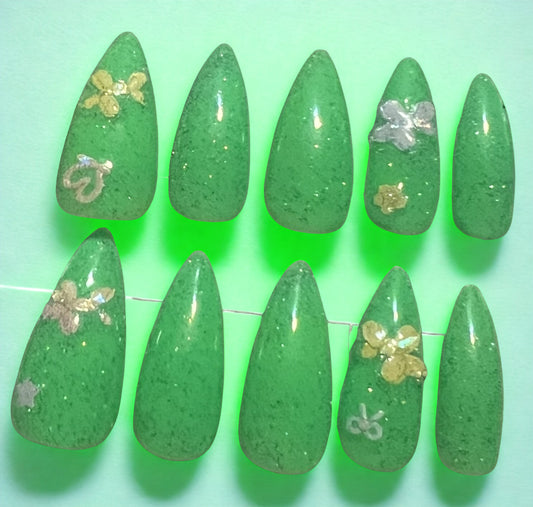 Legacy in Neon tribute press-on nails in neon green with a multi-colored holographic glitter topcoat. Decorated with stickers of balloon dogs, hearts, stars, and bows. Medium stiletto shape. Part of the Logan Harrel tribute collection available in pink, green, yellow, and orange.