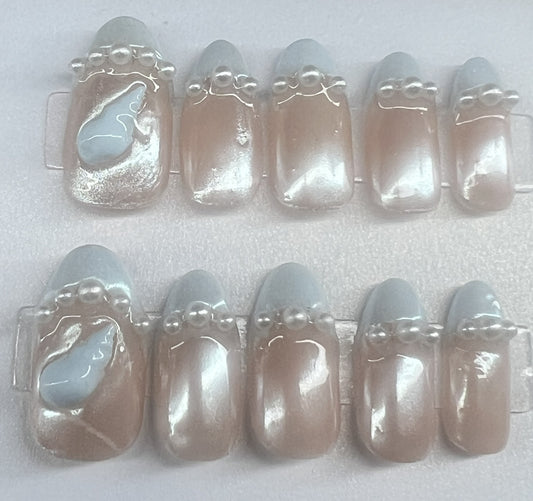 round bridal press on nails featuring a nude base, pale blue French tips, and a row of white pearls on each nail.