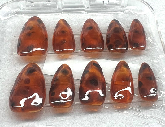 Luxury hand-painted tortoise shell press-on nails. Features multiple layers of translucent amber jelly and dark espresso spots to create a realistic 3D depth. High-gloss finish on a medium almond shape.